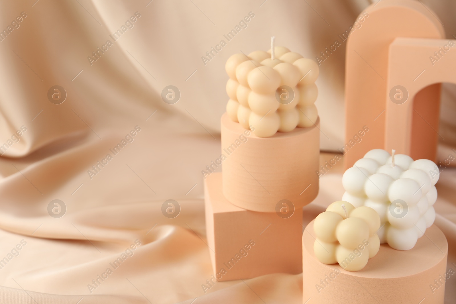 Photo of Beautiful bubble candles and geometric figures on beige fabric, space for text