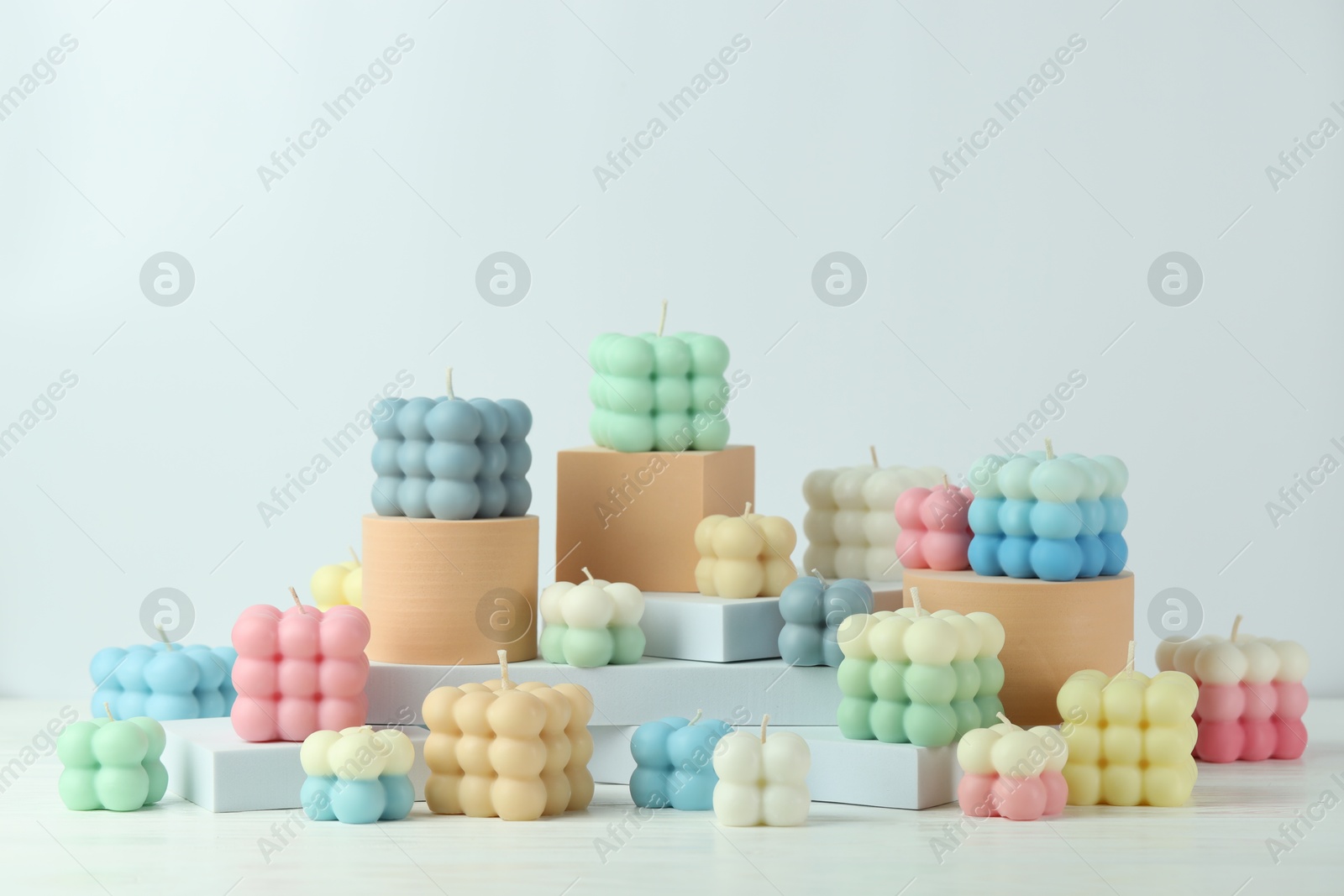 Photo of Many beautiful bubble candles and podiums on white table