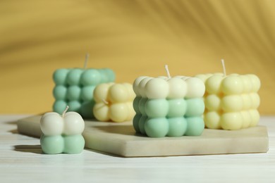 Photo of Beautiful bubble candles on white wooden table, closeup