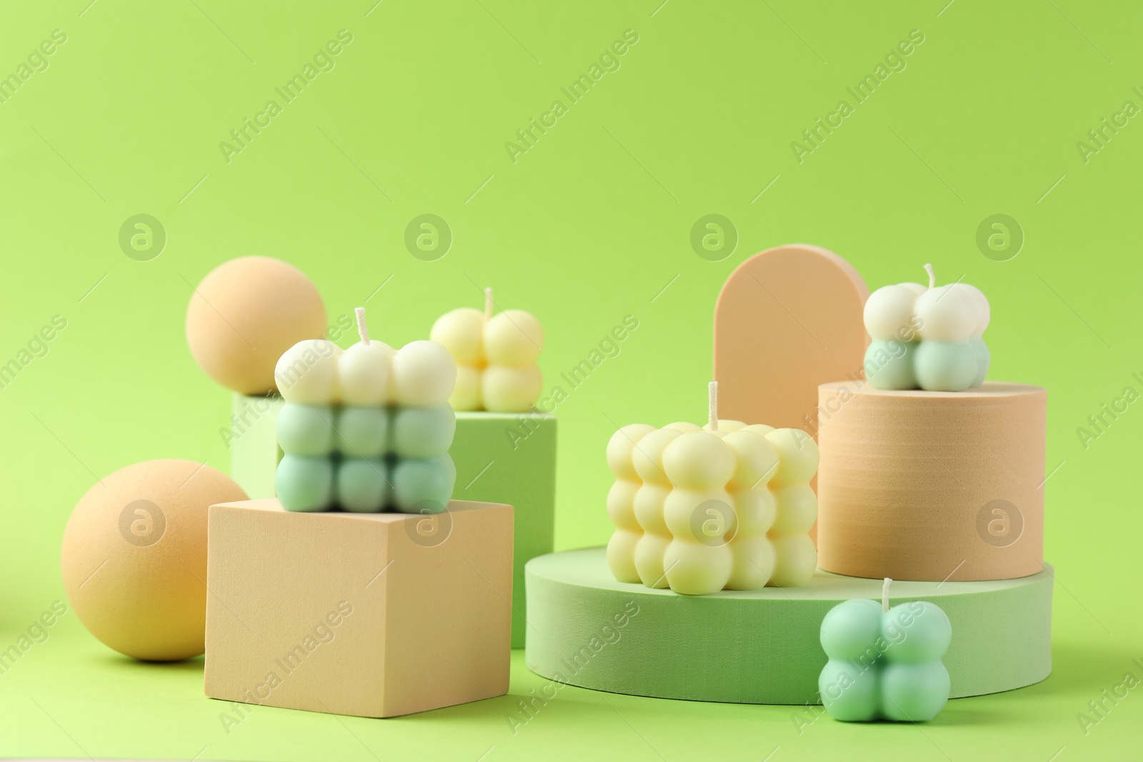 Photo of Beautiful bubble candles and geometric figures on green background