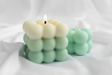 Photo of Stylish bubble candles on white cloth, closeup