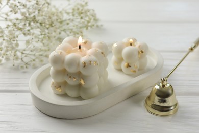 Photo of Stylish bubble candles, snuffer and gypsophila flowers on white wooden table, closeup