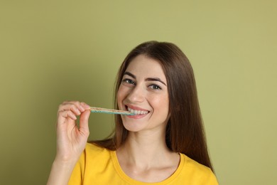 Photo of Young woman eating tasty rainbow sour belt on olive background