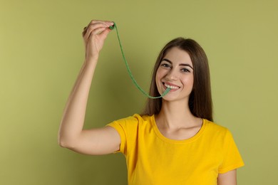 Young woman eating tasty gummy candy on olive background