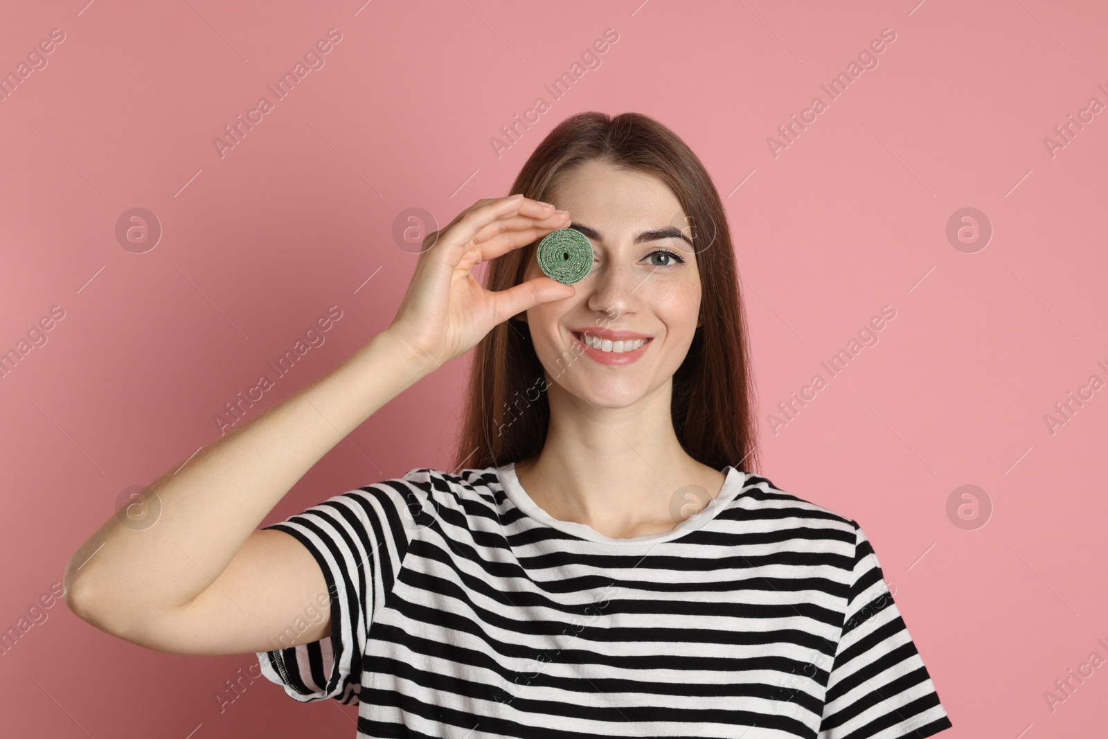 Photo of Happy young woman with tasty gummy candy on pink background