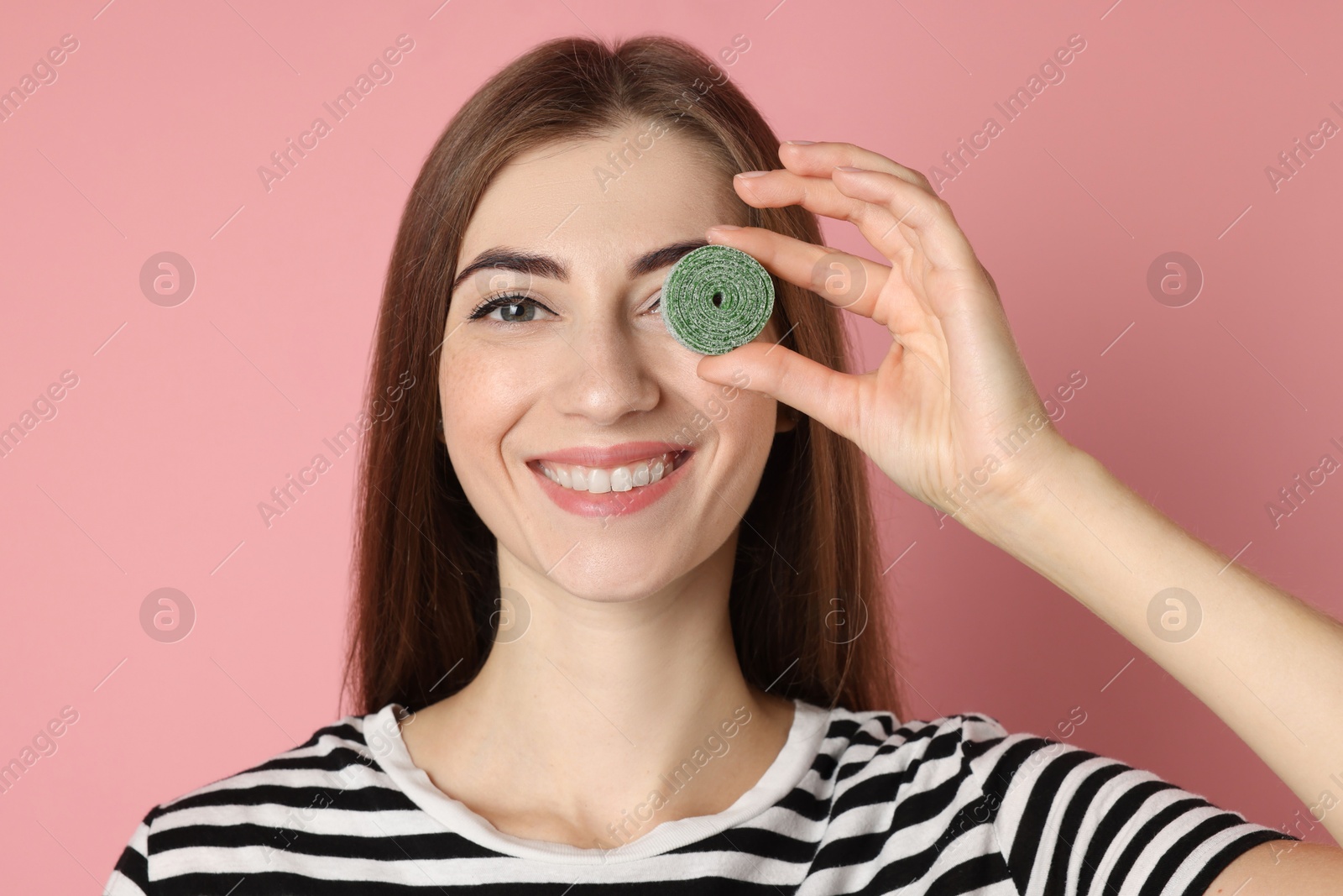 Photo of Happy young woman with tasty gummy candy on pink background