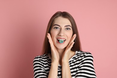 Young woman eating tasty gummy candy on pink background