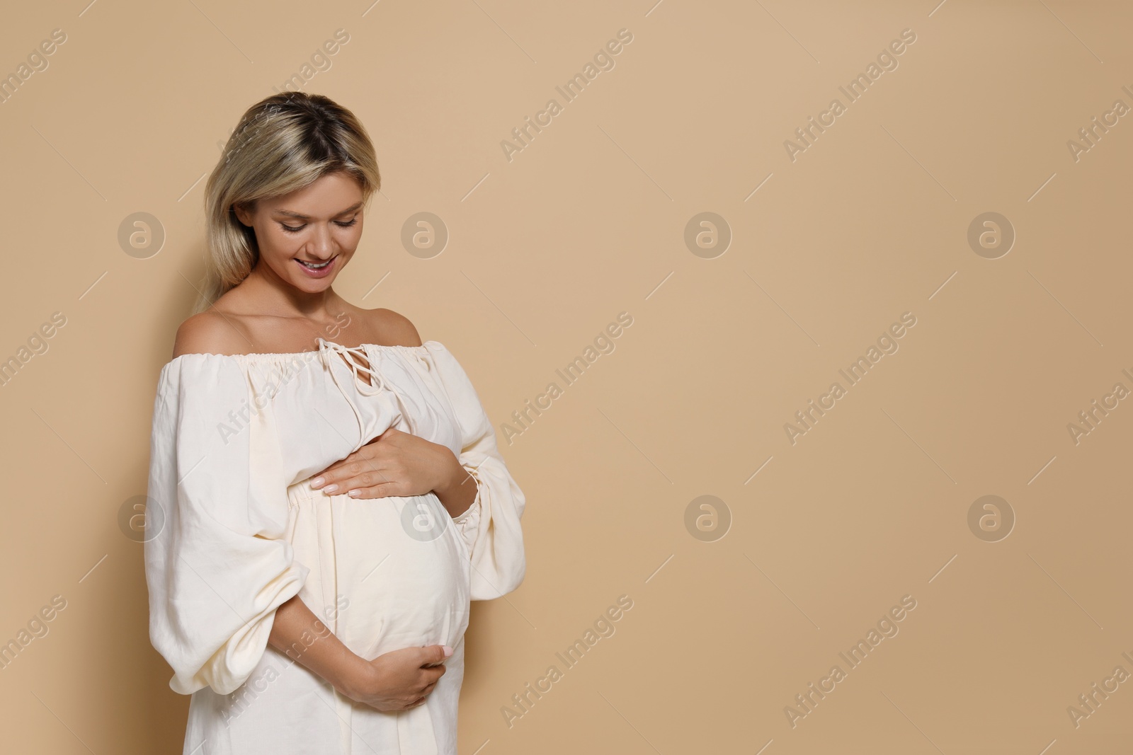 Photo of Portrait of beautiful pregnant woman on beige background, space for text