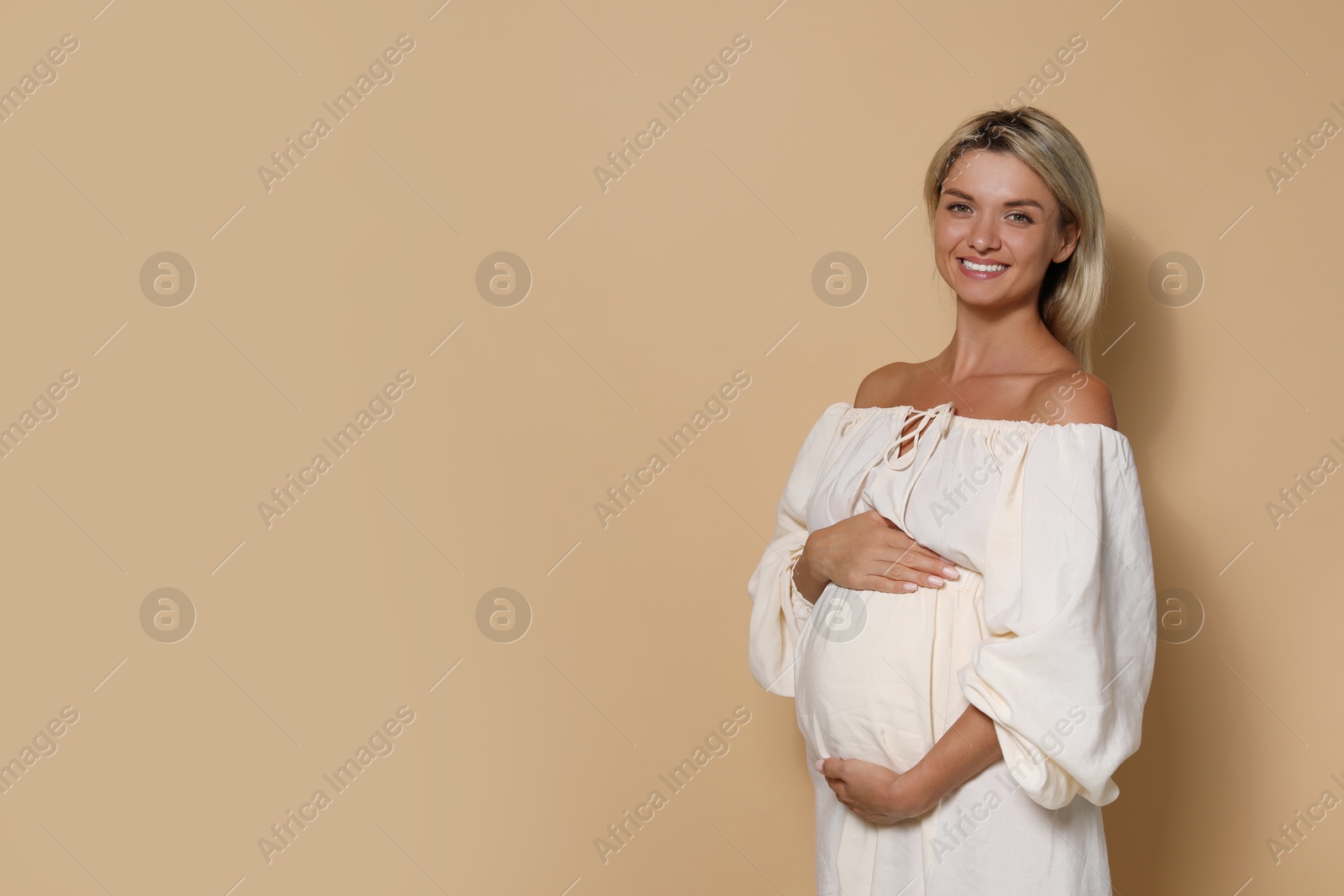 Photo of Portrait of beautiful pregnant woman on beige background, space for text