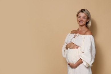 Photo of Portrait of beautiful pregnant woman on beige background, space for text