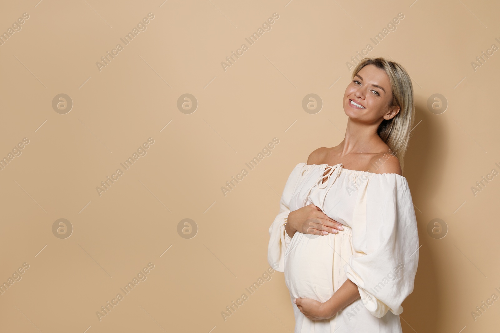 Photo of Portrait of beautiful pregnant woman on beige background, space for text