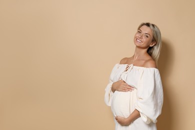 Portrait of beautiful pregnant woman on beige background, space for text