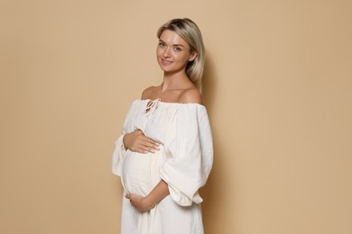 Portrait of beautiful pregnant woman on beige background