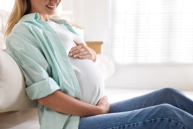 Photo of Pregnant woman on floor at home, closeup