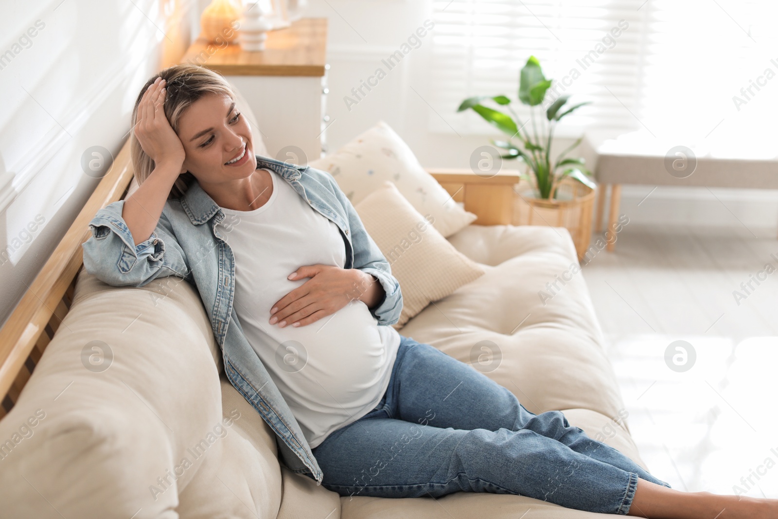 Photo of Portrait of beautiful pregnant woman on sofa at home