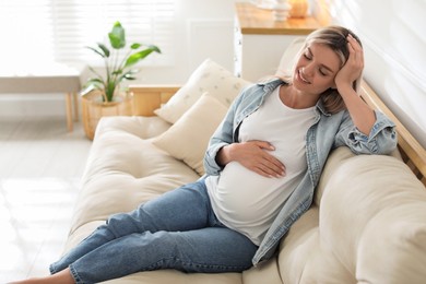 Portrait of beautiful pregnant woman on sofa at home