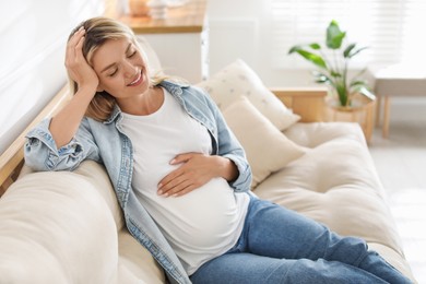 Portrait of beautiful pregnant woman on sofa at home