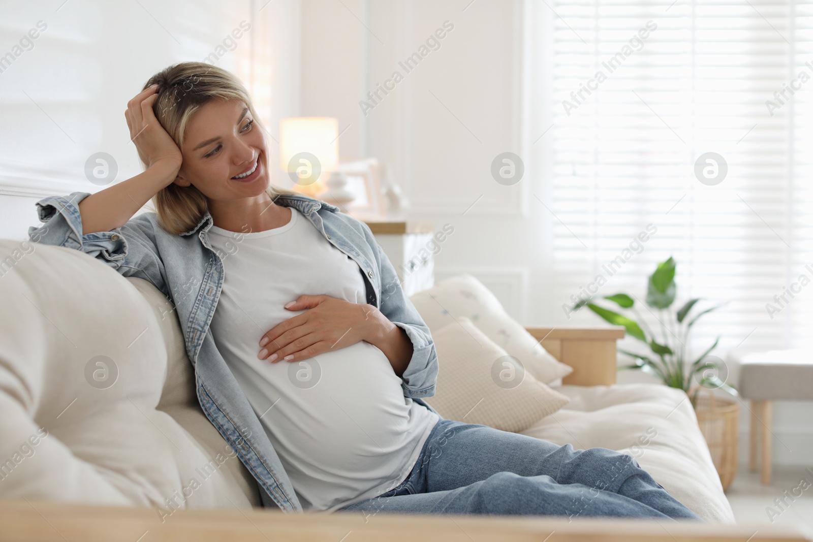 Photo of Portrait of beautiful pregnant woman on sofa at home