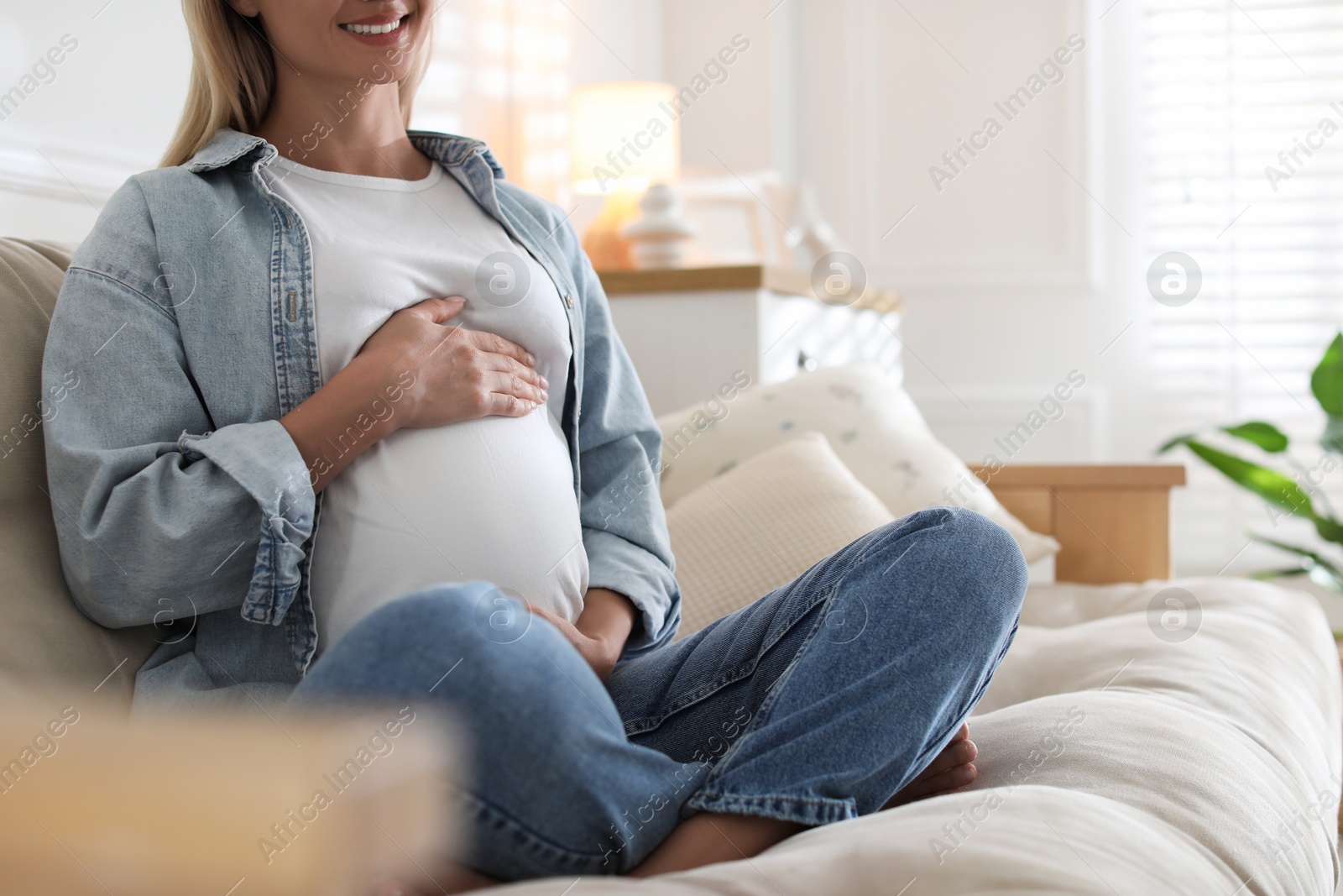 Photo of Pregnant woman on sofa at home, closeup