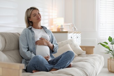 Portrait of beautiful pregnant woman on sofa at home