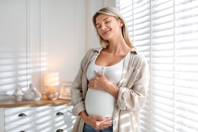 Photo of Portrait of beautiful pregnant woman near window at home