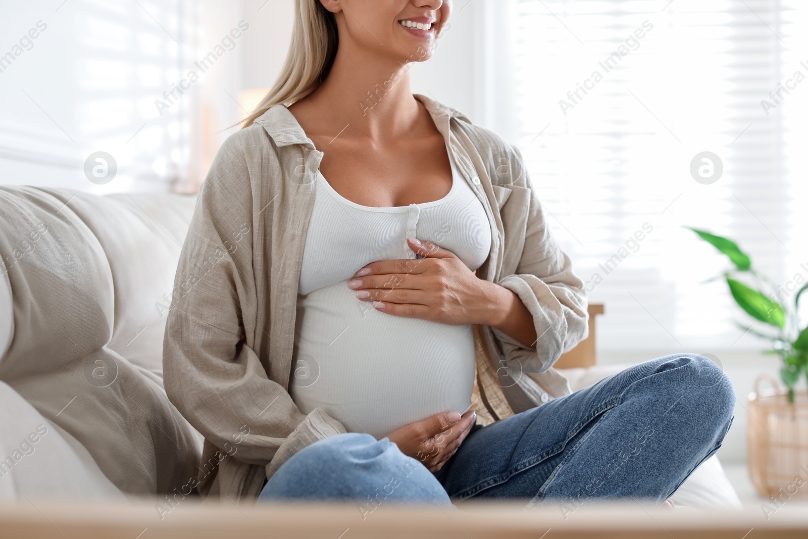 Photo of Pregnant woman on sofa at home, closeup