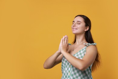 Photo of Young student grateful about her good exam result on orange background, space for text