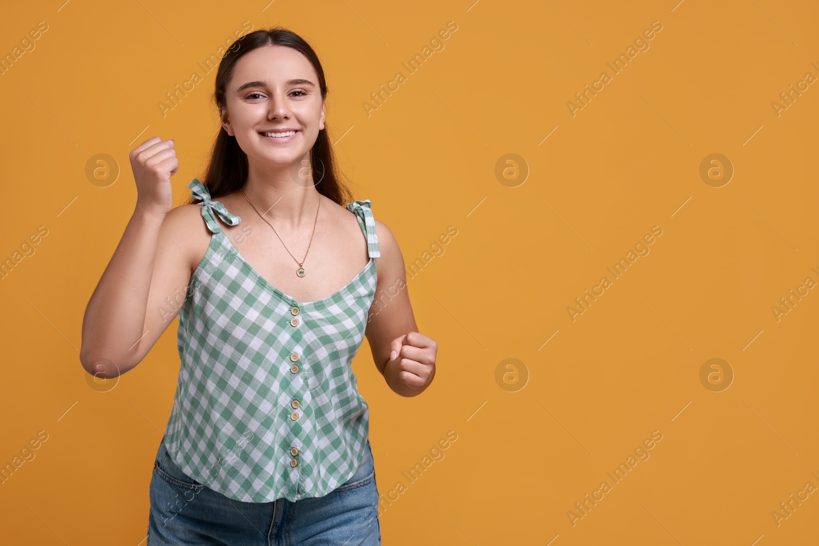 Photo of Happy young student on orange background, space for text