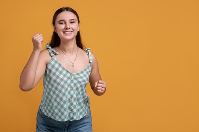 Photo of Happy young student on orange background, space for text