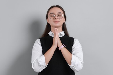 Photo of Young student praying for good exam result on grey background