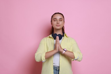 Photo of Young student praying for good exam result on pink background