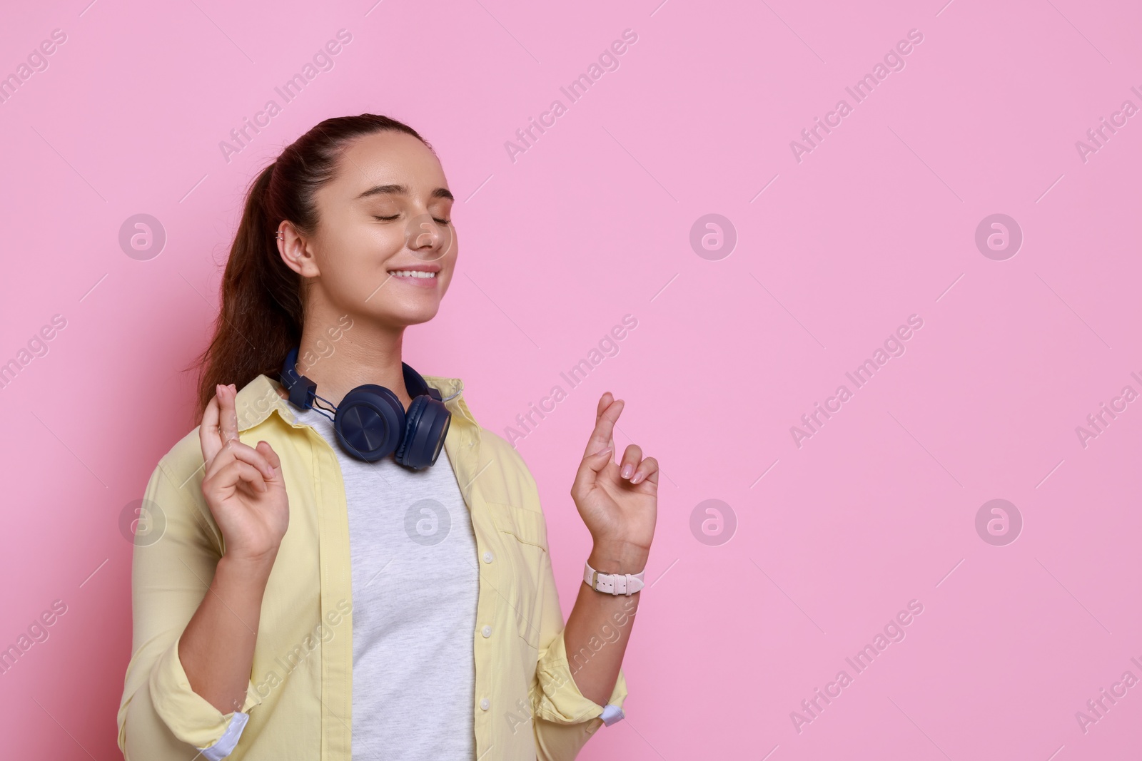 Photo of Excited young student crossing fingers on pink background, space for text. Hope for good exam result