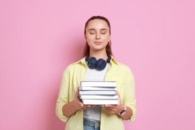 Photo of Young student with stack of books on pink background