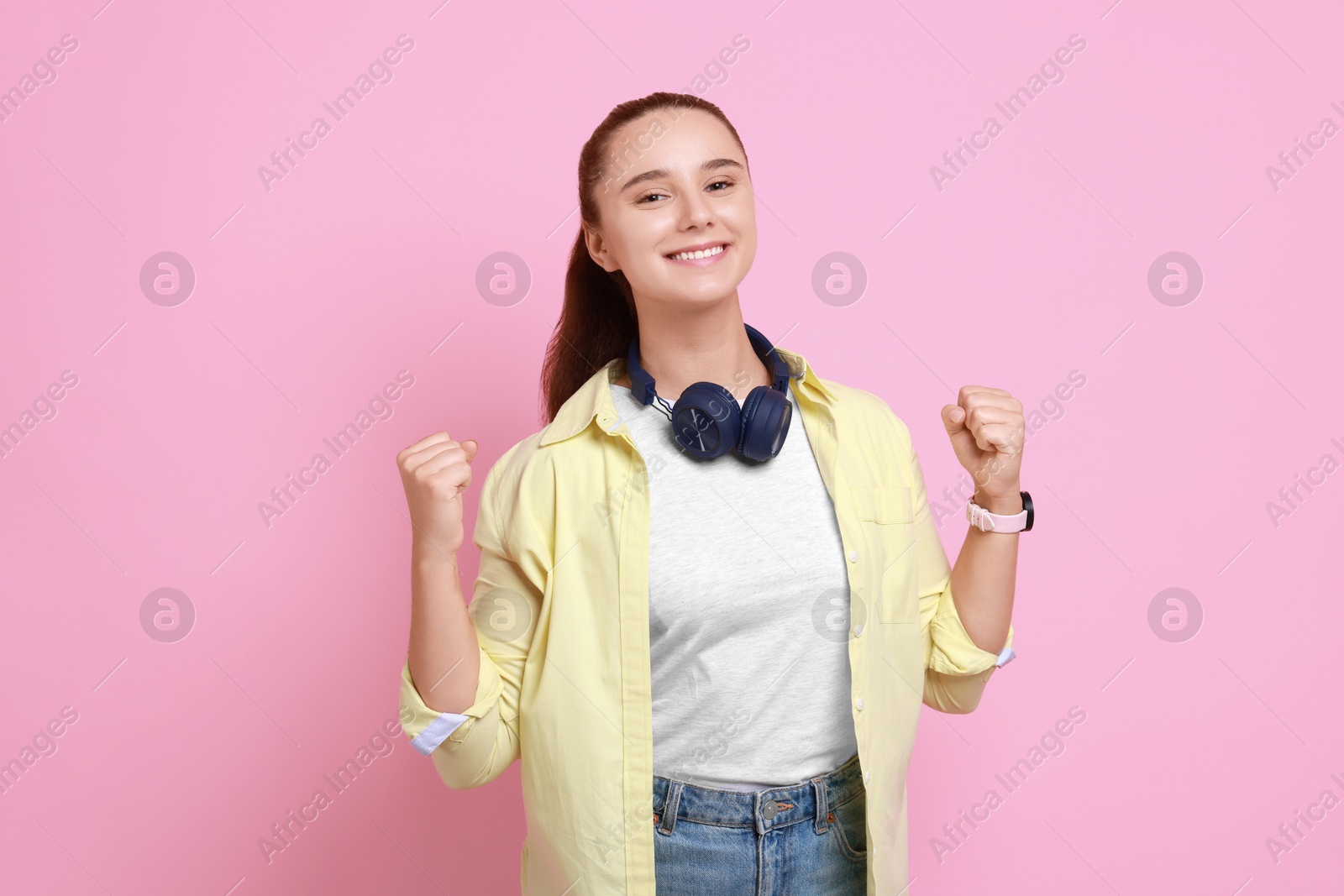 Photo of Happy young student with headphones on pink background