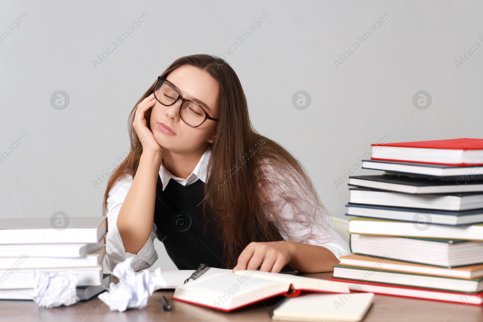 Photo of Young student having stress before exam at desk against grey background