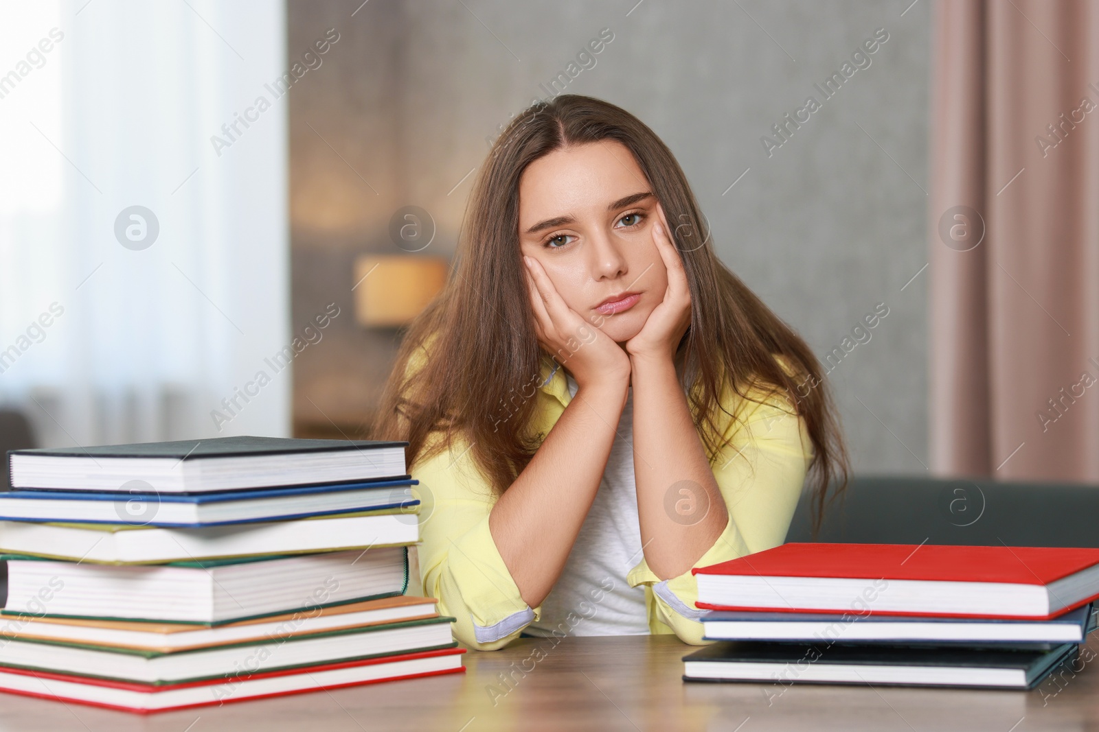 Photo of Young student with books having stress before exam at wooden table