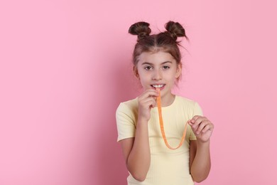 Photo of Happy girl eating tasty gummy candy on pink background. Space for text