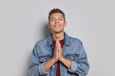 Photo of Student with clasped hands happy about his good exam result on grey background