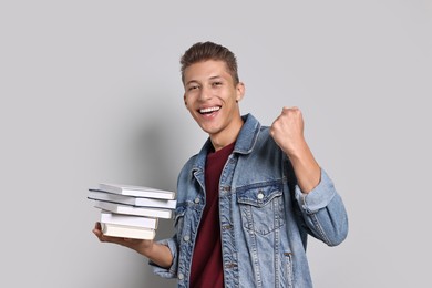 Photo of Happy student with stack of books on grey background