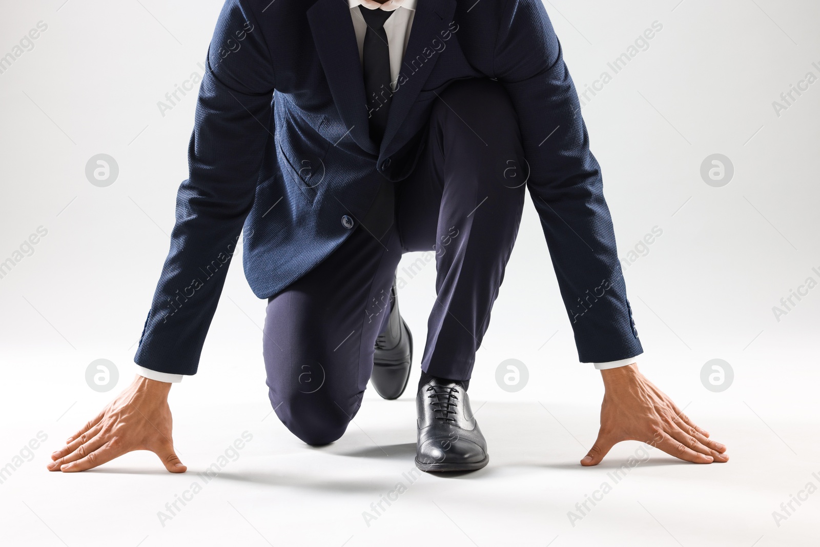 Photo of Businessman in starting position for run on white background, closeup