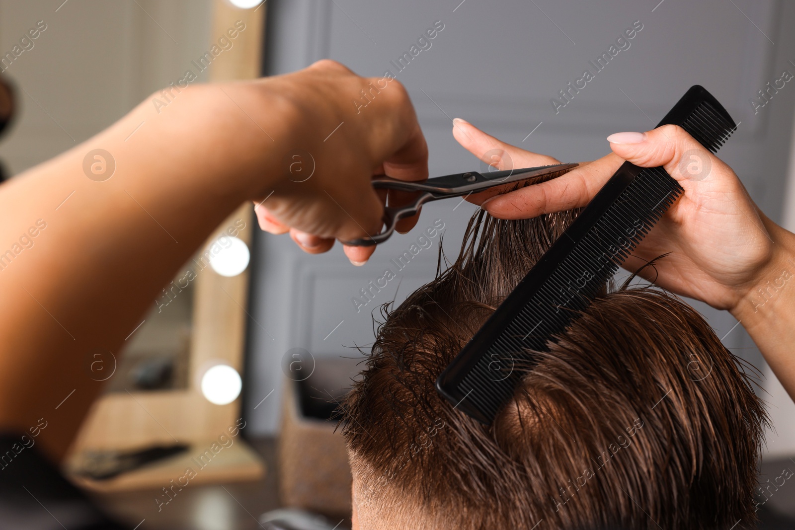 Photo of Professional hairdresser cutting client's hair with scissors in barbershop, closeup