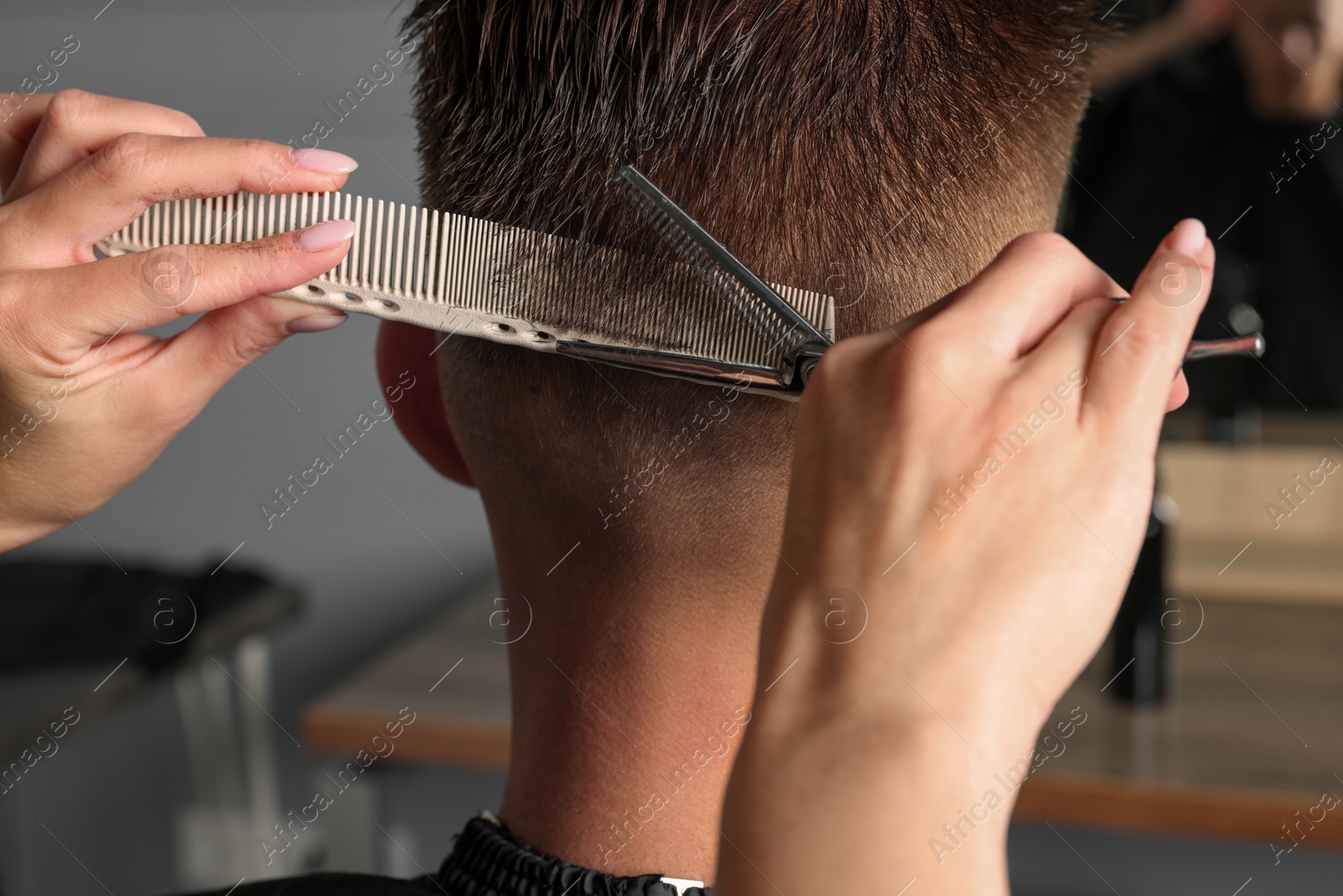 Photo of Professional hairdresser cutting client's hair with scissors in barbershop, closeup