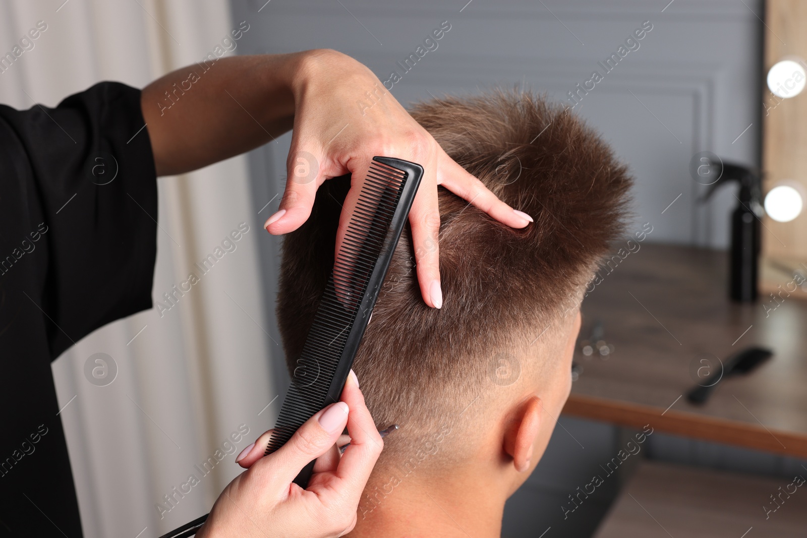 Photo of Professional barber making stylish haircut in salon, closeup