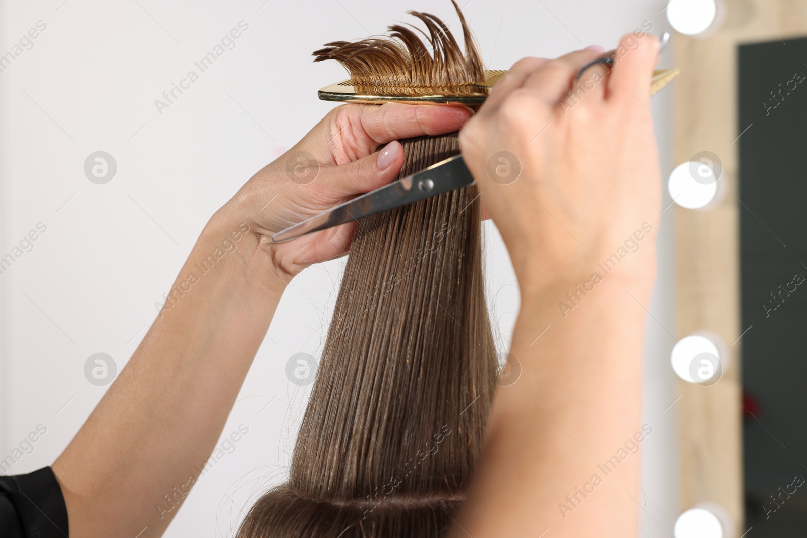 Photo of Hairdresser cutting client's hair with scissors in salon, closeup