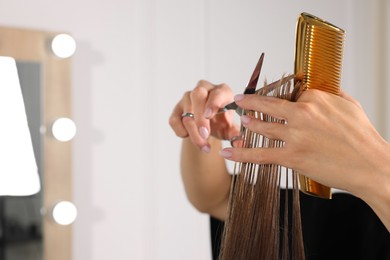 Photo of Hairdresser cutting client's hair with scissors in salon, closeup. Space for text