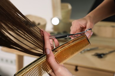 Photo of Hairdresser cutting client's hair with scissors in salon, closeup