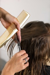 Photo of Hairdresser cutting client's hair with scissors in salon, closeup