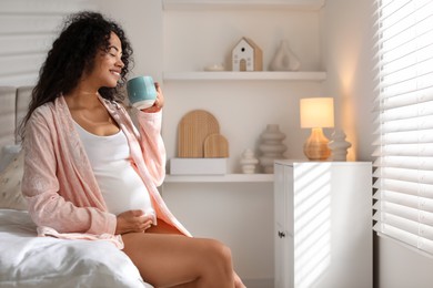 Photo of Portrait of beautiful pregnant with cup of drink on bed at home