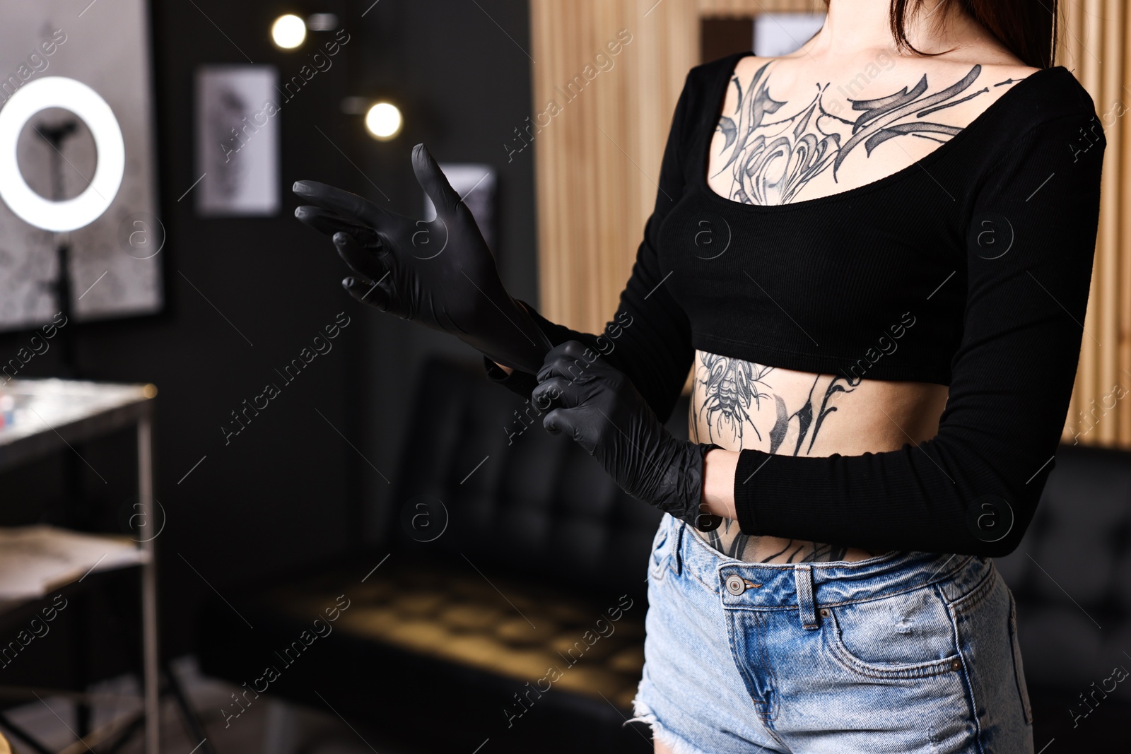 Photo of Professional tattoo artist wearing gloves in salon, closeup. Space for text