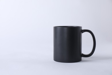 Photo of One blank black mug on white background. Mockup for design